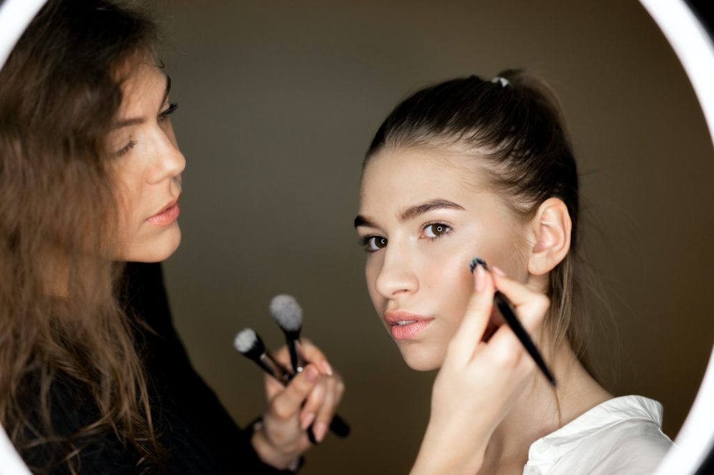 Makeup artist the charming girl is doing makeup to a beautiful young girl